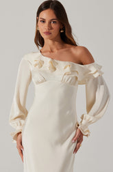 A woman is wearing an elegant, off-white, satin dress featuring a one-shoulder design with ruffled detailing along the neckline and shoulder. The dress has long, puffed sleeves with gathered cuffs.